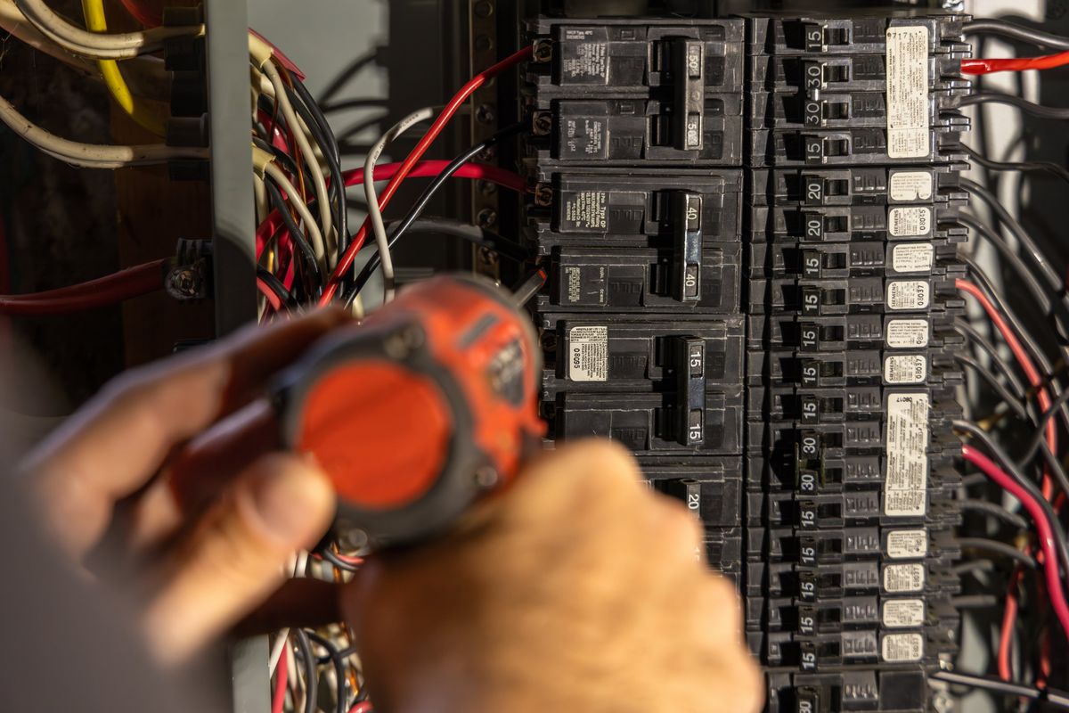 Electrician testing circuit breakers in a residential panel with a meter