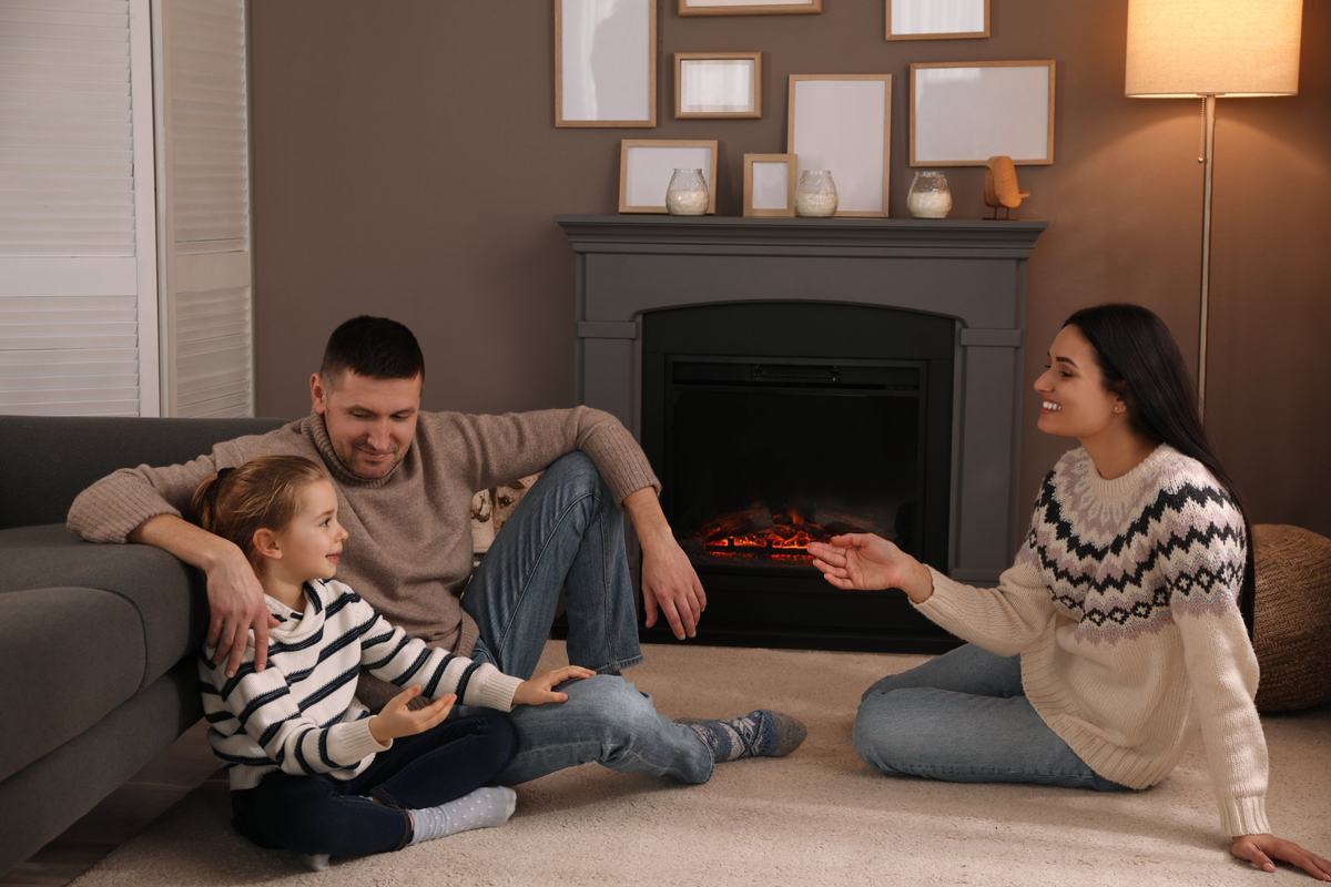 Family sitting on the living room floor in sweaters, warm at home on a winter evening