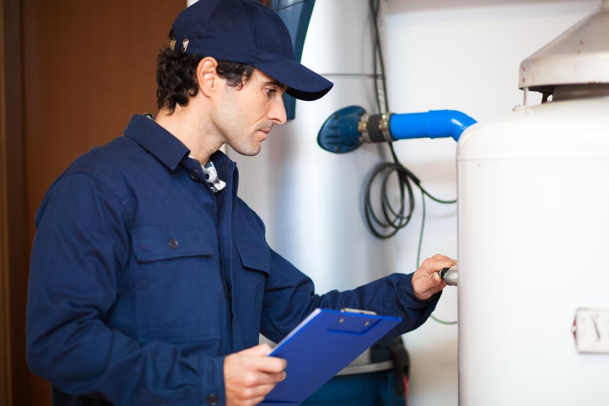 Technician inspecting a water heater with a clipboard